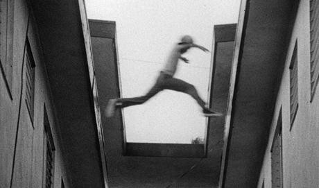 still from the movie; from a ground perspective, it shows a kid jumping from one roof to another.